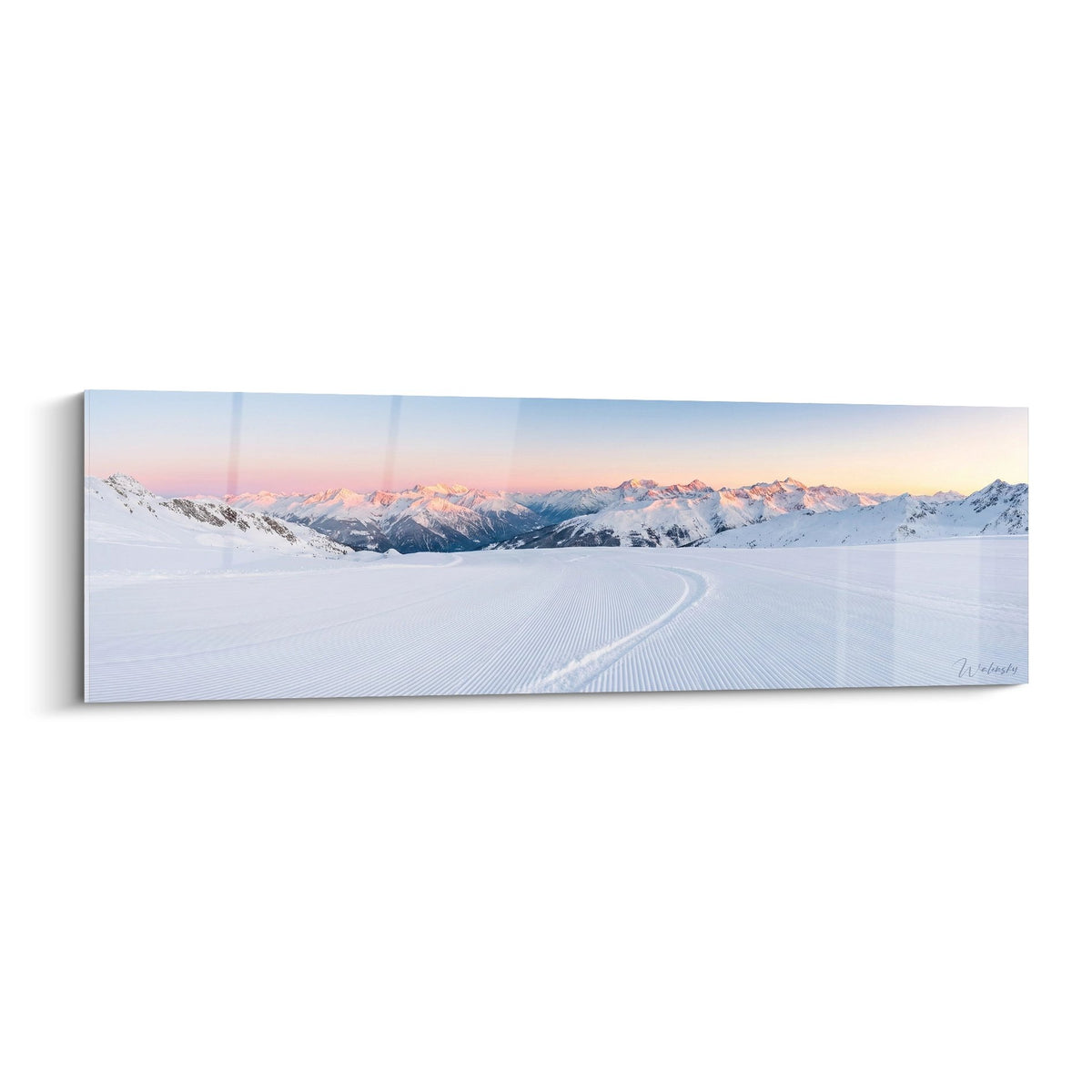 Tableau panoramique piste de ski damee au coucher du soleil avec montagnes enneigees et ciel rose